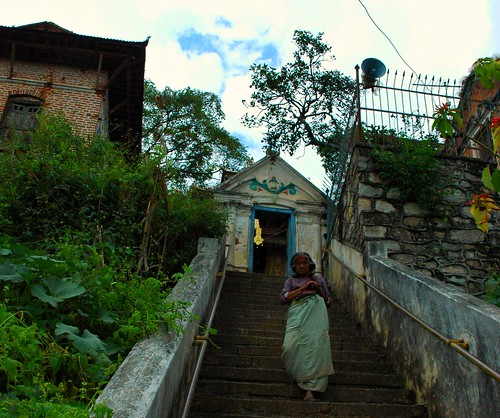 Woman on the stairs at an entrance of the Buddhist shrine where the Pamting brothers statue of Vajrajogini Statue is housed, Pharping (Yangleshod), Nepal by Wonderlane