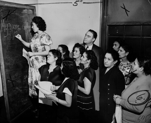 Maria Vargas writes her name on the blackboard during ILGWU Local 91's English class for Spanish-speaking members, taught by William Waens.