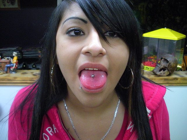 latina getting a Tongue piercing by Cirilo Serrano at Coffin City Tattoo