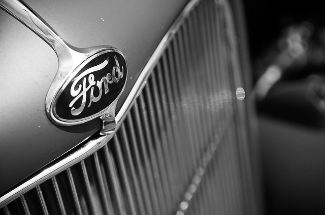 The classic style ford logo badged over the tal front end grill of a classic