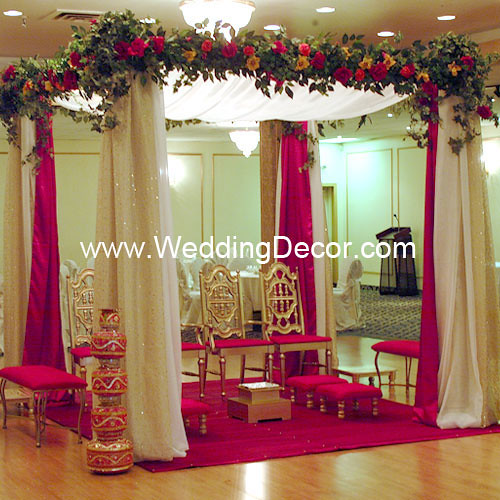A wedding mandap in red and ivory with gold sparkle accets and silk floral