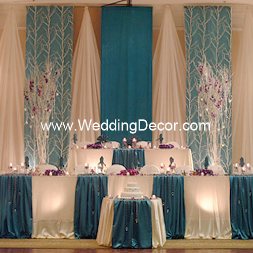 A turquoise and white wedding backdrop with matching head table and cake