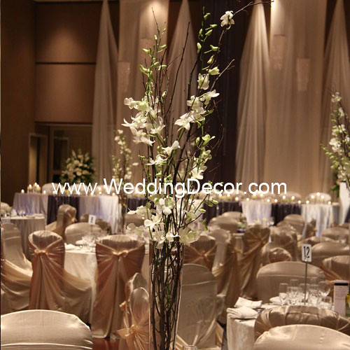 A wedding centerpiece in a tall pilsner vase with natural birch branches and