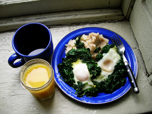 fried eggs in spinach over mashed potatoes and cannellini beans with coffee and OJ