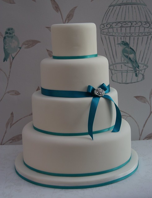 Simple 4 tier wedding cake with thin satin ribbons finished with a vintage 