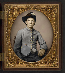 [Unidentified young soldier in Confederate shell jacket, Hardee hat with Mounted Rifles insignia and plume with canteen and cup] (LOC)