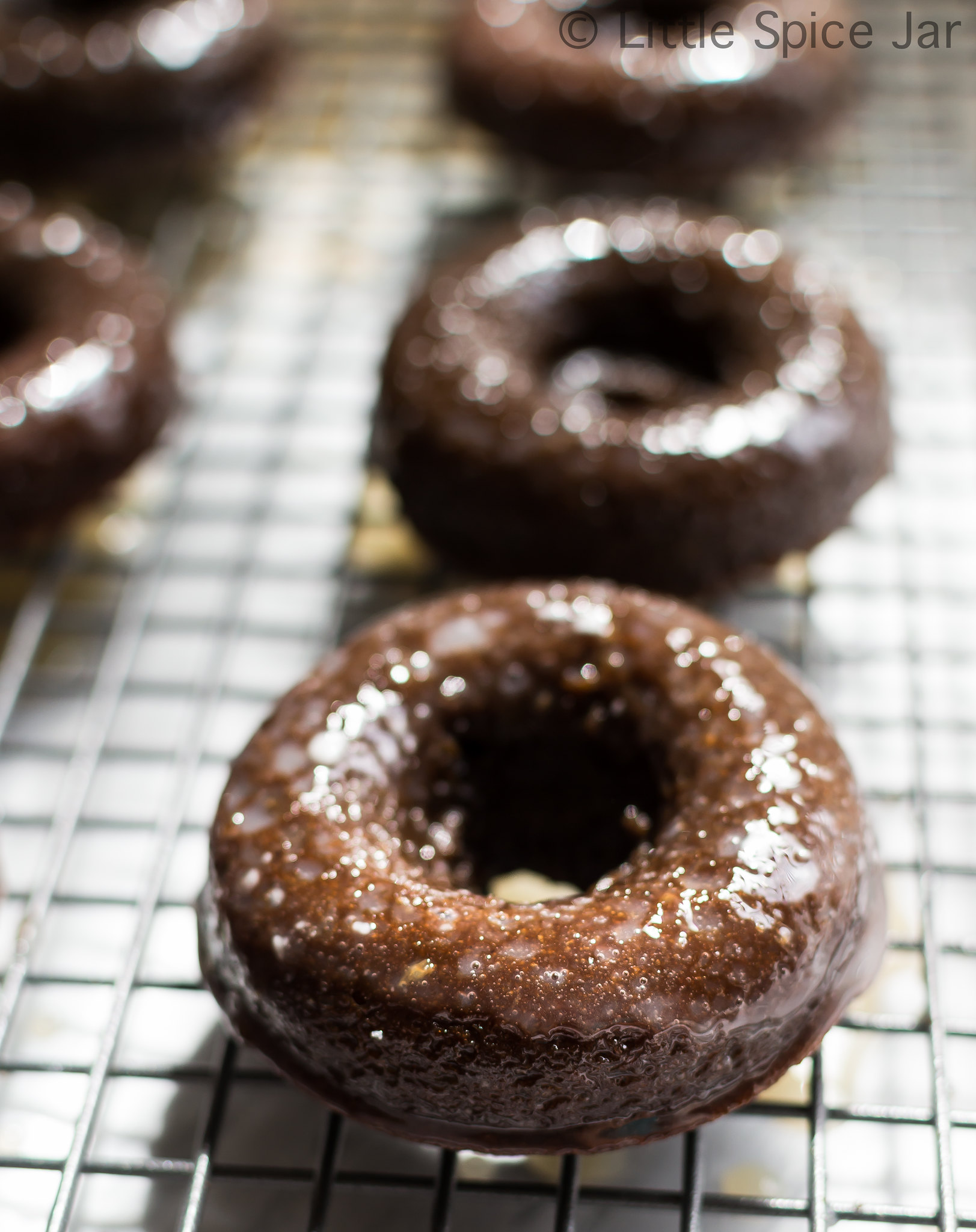 baked and glazed chocolate donuts on wire rack
