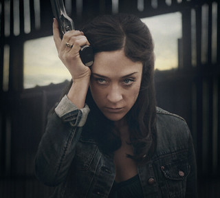 Chloe Sevigny holds a gun up to her face and looks intense