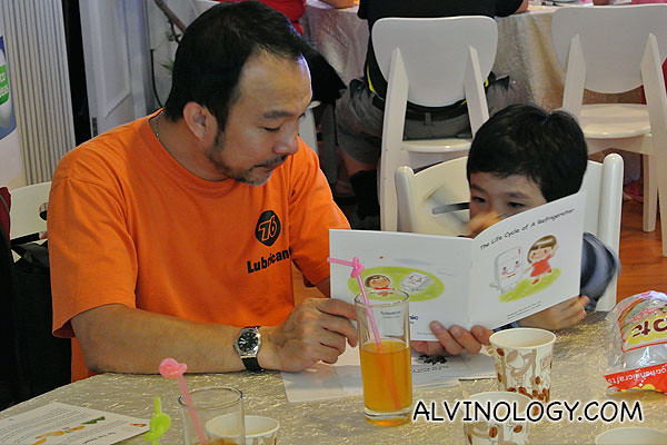 A father reading a Panasonic eco book on Fridges to his little son