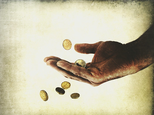 Ilustración: unas monedas se escapan entre los dedos de una mano