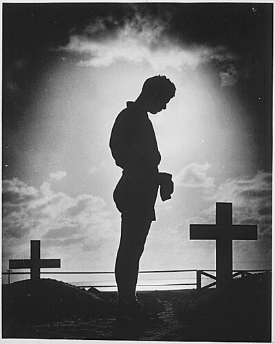 A Coast Guardsman stands in silent reverence beside the resting place of a comrade., 1944