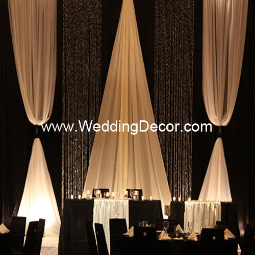 A black and ivory wedding backdrop with matching head table and cake table