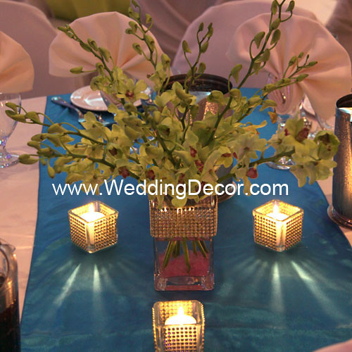 A wedding centerpiece in a small square vase with pink crushed glass gold 