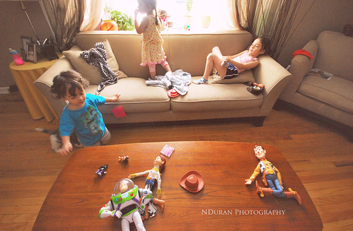 Several children play on a couch and around a coffee table