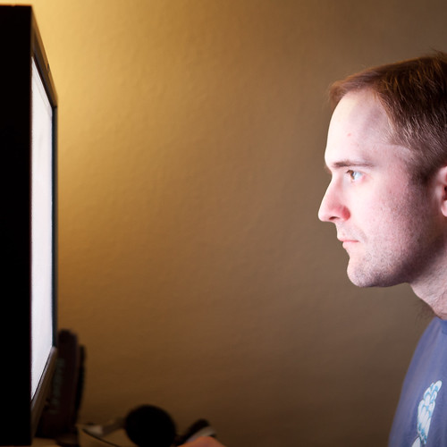 A man stares at a bright computer screen.