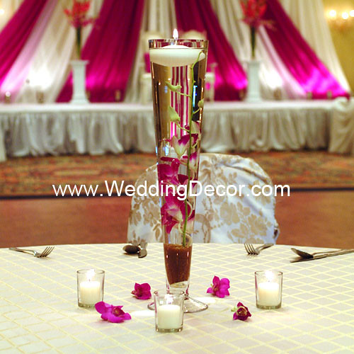 A wedding centerpieces with gold crushed glass fuchsia orchid stems and 