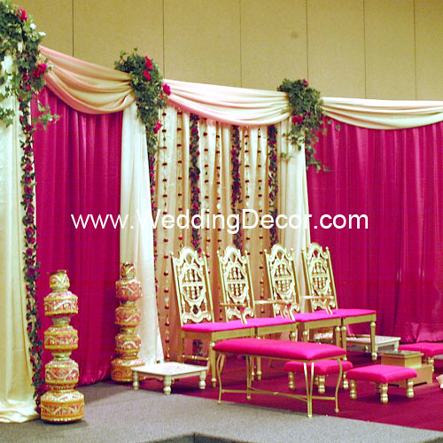 A wedding mandap in gold and red with silk floral arrangments and hanging 