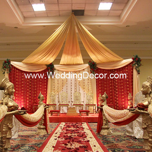 A wedding ceremony mandap in red gold and ivory with aisle decor and flower