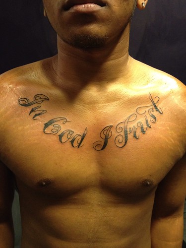 In god I trust script chest tattoo by Wes Fortier