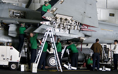 Sailors perform maintenance on EA-6B Prowler in hangar bay.
