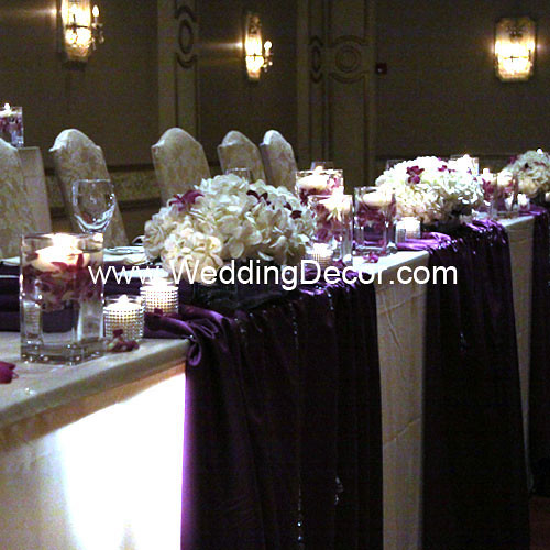 Head table decorations for a wedding reception in royal purple and ivory 