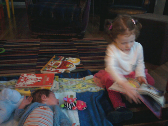Reading to her baby brother.