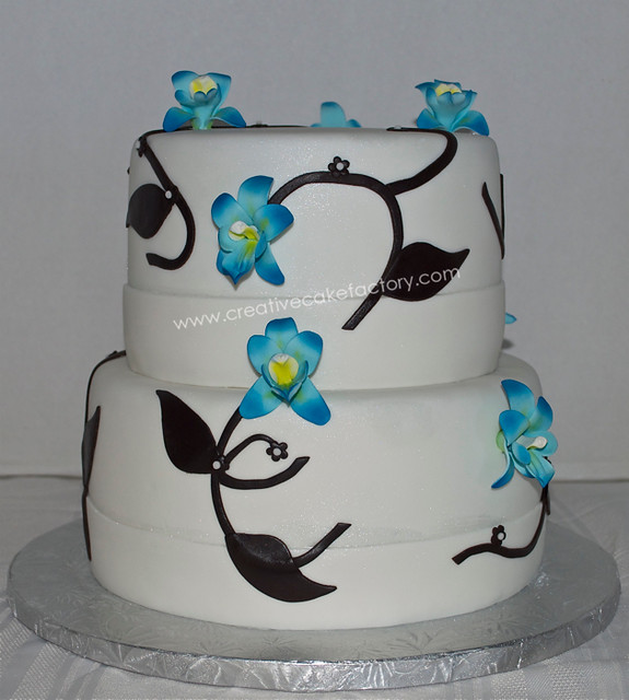 2 tier wedding cake covered in white fondant with blue gumpaste orchids and 