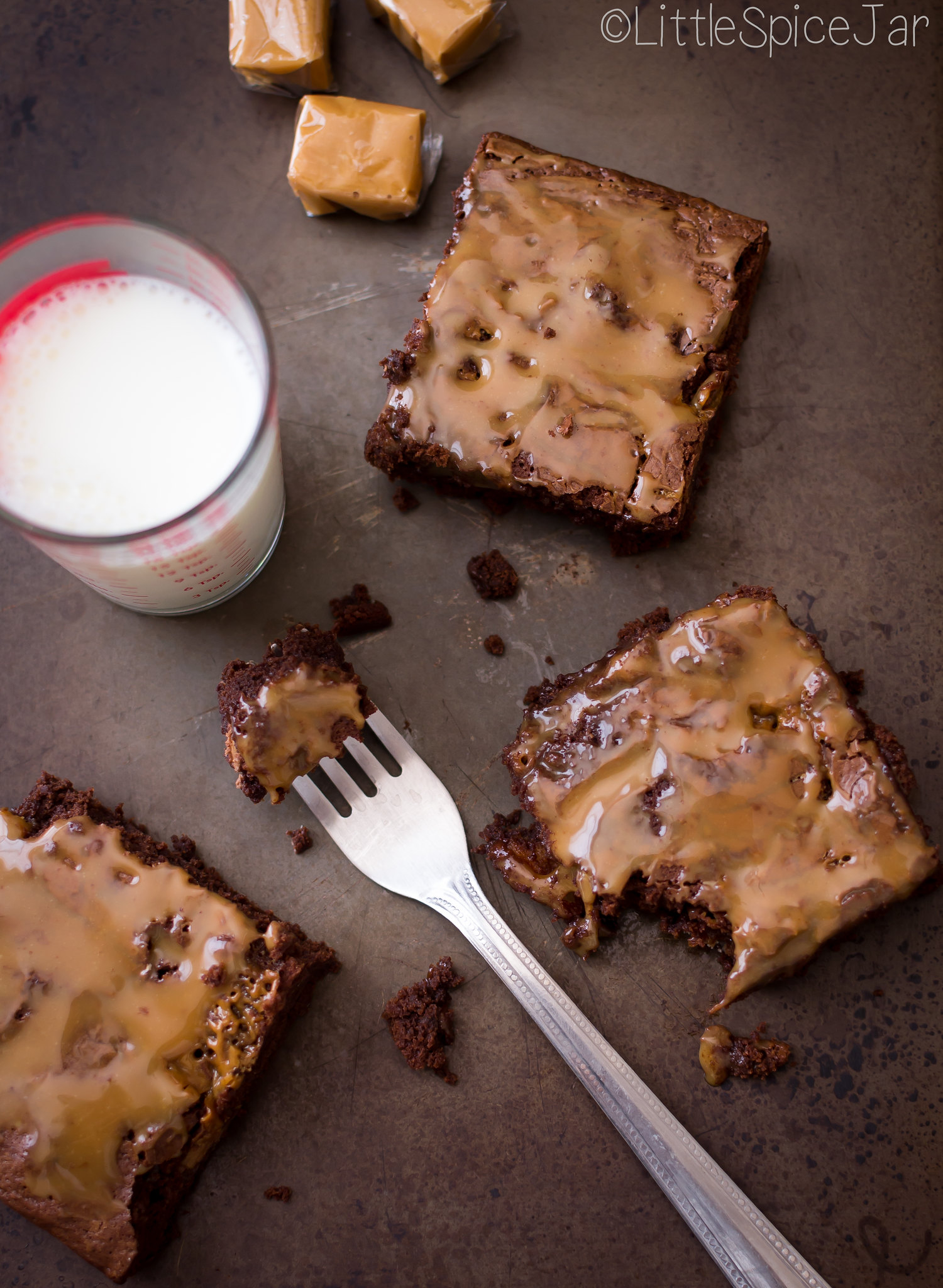 prepared Twix caramel brownies cut into squares in sheet pan with a glass of milk 