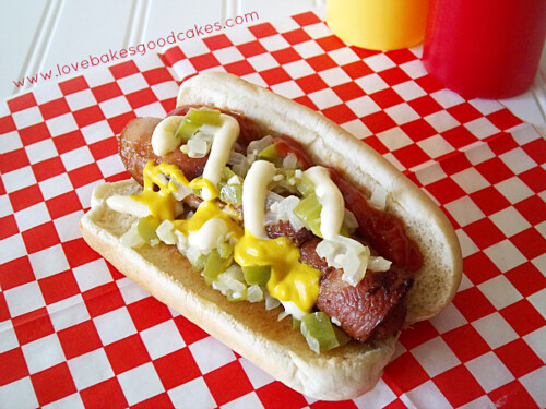 Gutter Dog with bun, ketchup, mustard, mayonnaise on red and white checkerboard place mat.  