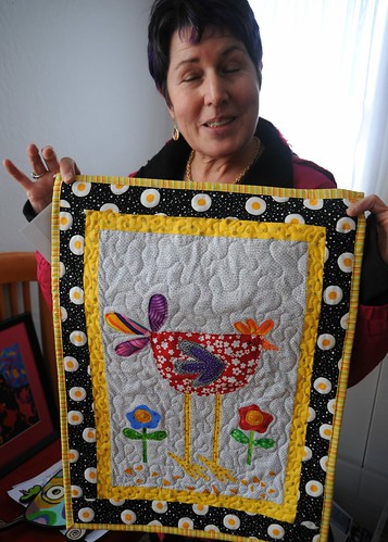 Eyes wide shut, with that expression! Debra Fitzgerald shows off a small fabric art from her collection, quilt surrounded by eggs, Lake Otis, Anchorage, Alaska, USA by Wonderlane
