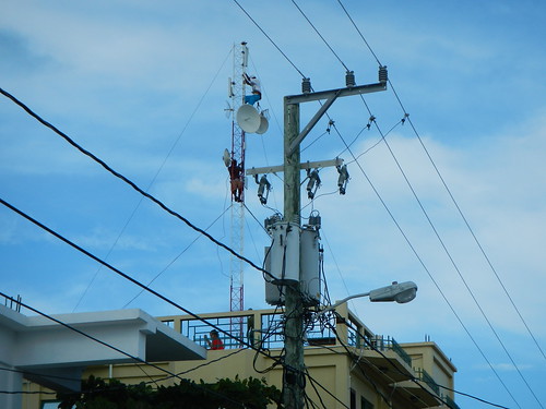 Workers climb high above Caye Caulker village skyline to maintain infrastructure