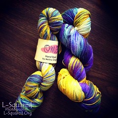Two hanks of hand-dyed yarn with sections in yellow, blues and purples.