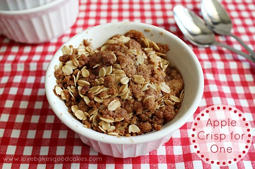 Apple Crisp for One in white bowl with spoons on red table cloth.