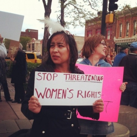 A Native woman holding a protest sign for women's rights