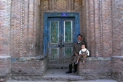 China - Kashgar - Man With Grandson Sitting In Front Of House - 11