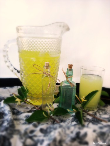 A pitcher of homemade Honeysuckle Lemonade and some honeysuckle floral water gifts
