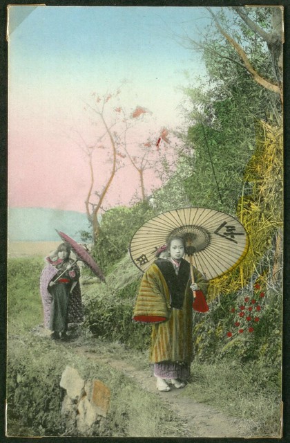 Two women with umbrellas children in child carriers. Japan