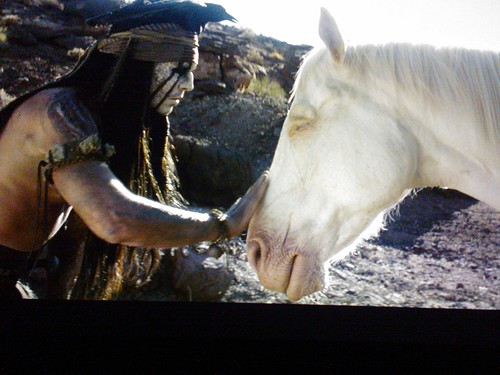 Tonto (Johnny Depp) wearing crow crown, petting Silver (played by Silver an 11 yr old quarter horse - upstaging everyone), a white spirit horse, The Lone Ranger, film, Northgate, Seattle, Washington, USA by Wonderlane