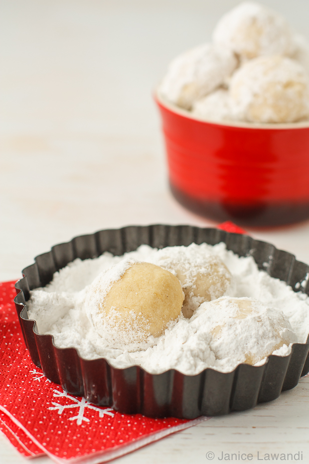 Coating snowball cookies in powdered sugar.