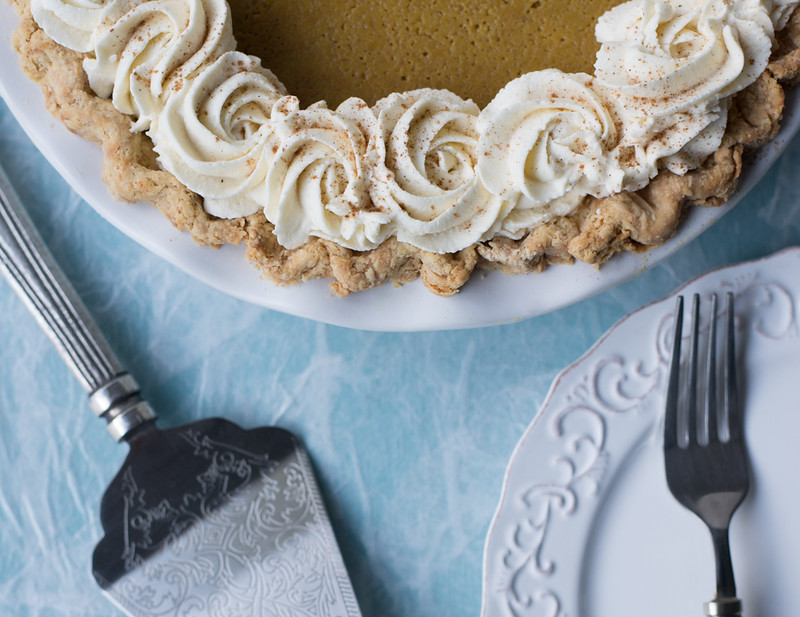 pumpkin pie with whipped cream swirls silver pie server white plate fork