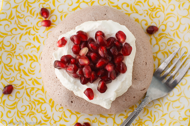 chocolate pavlova with whipped cream and pomegranate seeds.