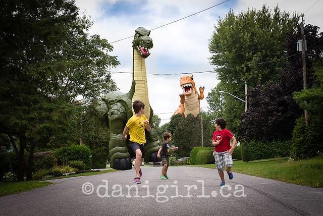 Photo of children pretending to run from a toy dinosaur