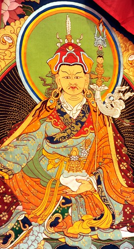 Tibetan Thangka of Padmasambhava, holding a bowl of nectar, vajra staff, halo, vulture feather in lotus hat, traditional garments, boots, gold & turquoise earrings, saint founder of Tibetan Buddhism, South Bay Vajrayana, Silicon Valley, California, USA by Wonderlane