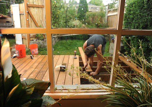 Stephen finishing the new deck, working with treated 2 by 4's, through the window, peace plant and spider plants, orange buckets, chevy truck, A Garden for the Buddha, Seattle, Washington, USA by Wonderlane