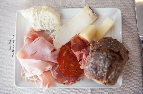 Plate of cheeses and charcuterie with a cranberry pecan roll