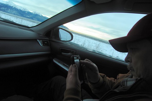 Ward Lane checking his smart phone as we drive Seward Highway along Turnagain Arm in the winter towards Kenai Pennisula, south east of Anchorage, Alaska, USA by Wonderlane