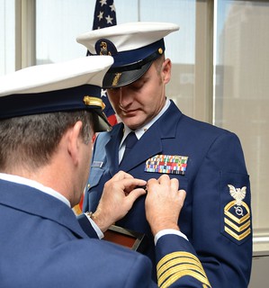 Chief Petty Officer Jeffrey Schmitt, a command center chief for the Coast Guard 9th District in Cleveland, recieves a retirement pin from Capt. Nicholas Bartolotta, the chief of response for the Coast Guard 9th District, during his retirement ceremony held at the Anthony J. Celebrezze Federal Building in Cleveland on Oct. 11, 2013.  Schmitt retired after serving in the Coast Guard for 22 years.