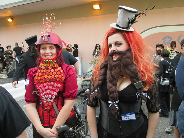 Two female steampunk cosplayers wearing elaborate beards and fancy women's clothes