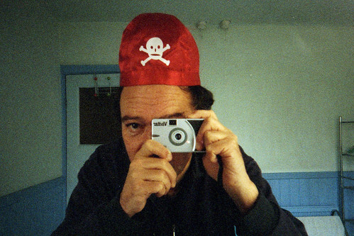 reflected self-portrait with Vivitar Ultra Wide & Slim camera and skull & cross-bones hat by pho-Tony