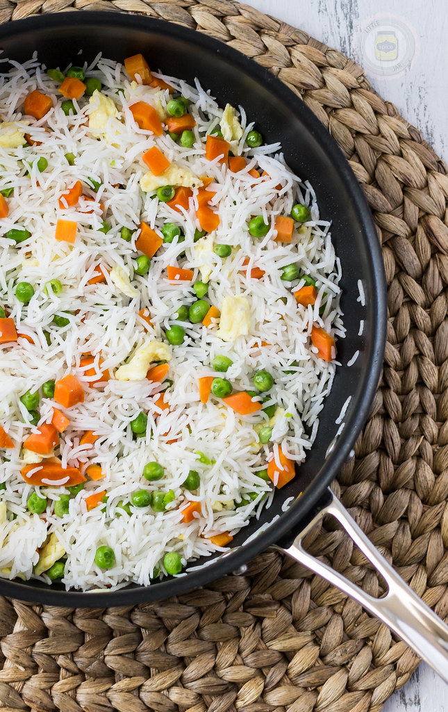 white rice mixed with vegetables in a black frying pan